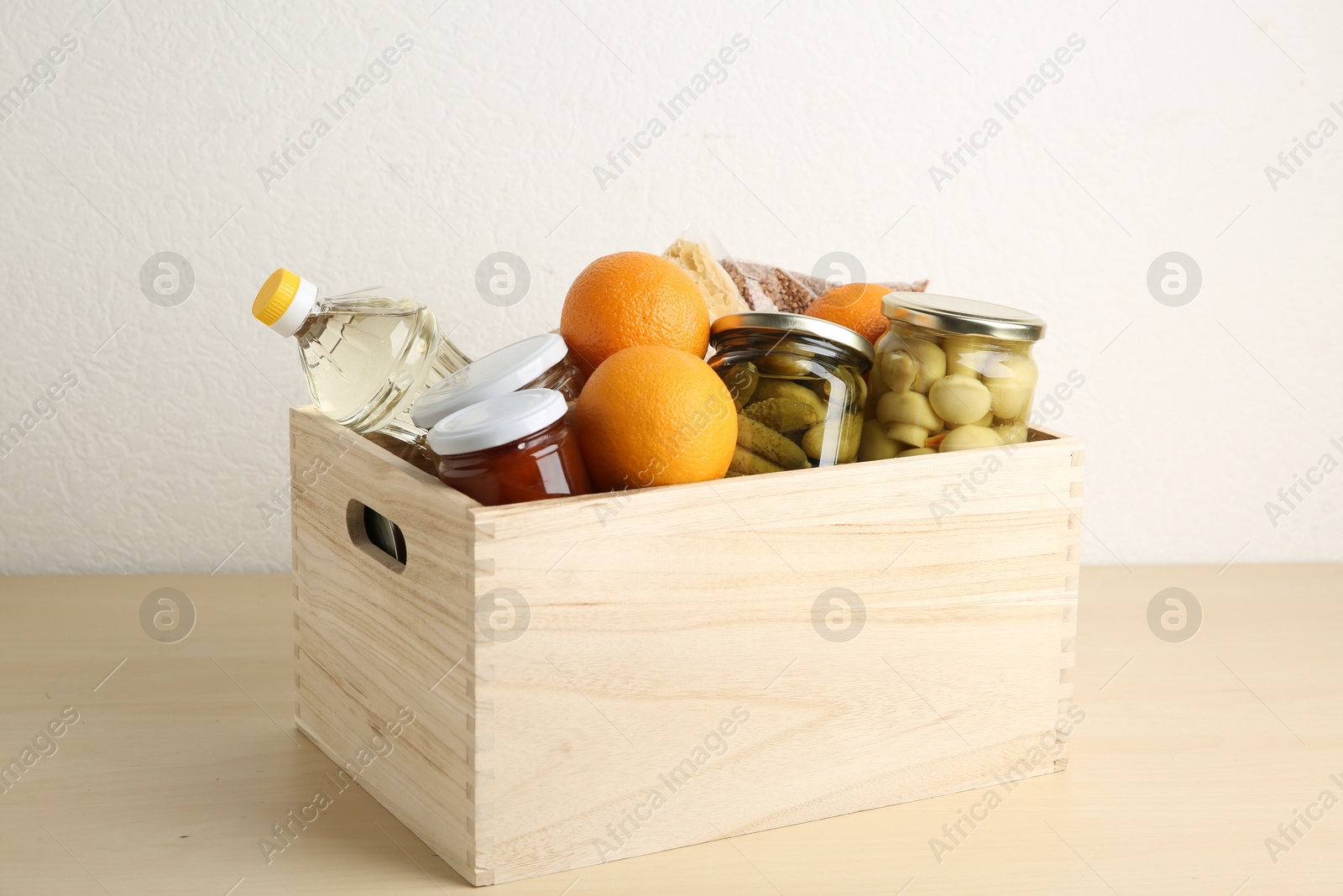 Photo of Different products in crate on wooden table. Food donation