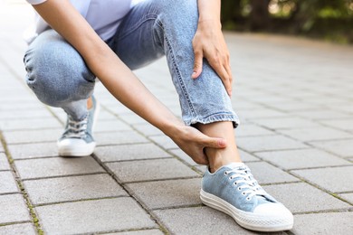 Photo of Woman suffering from foot pain outdoors, closeup