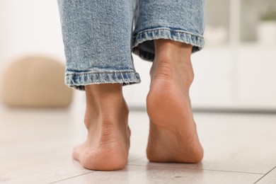 Photo of Woman suffering from foot pain at home, closeup