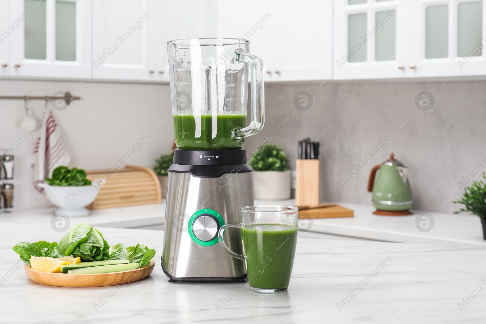 Photo of Modern blender with smoothie and ingredients on white marble table in kitchen