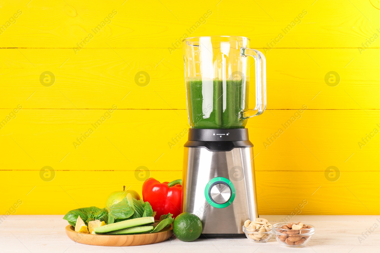 Photo of Modern blender with smoothie and ingredients on light wooden table