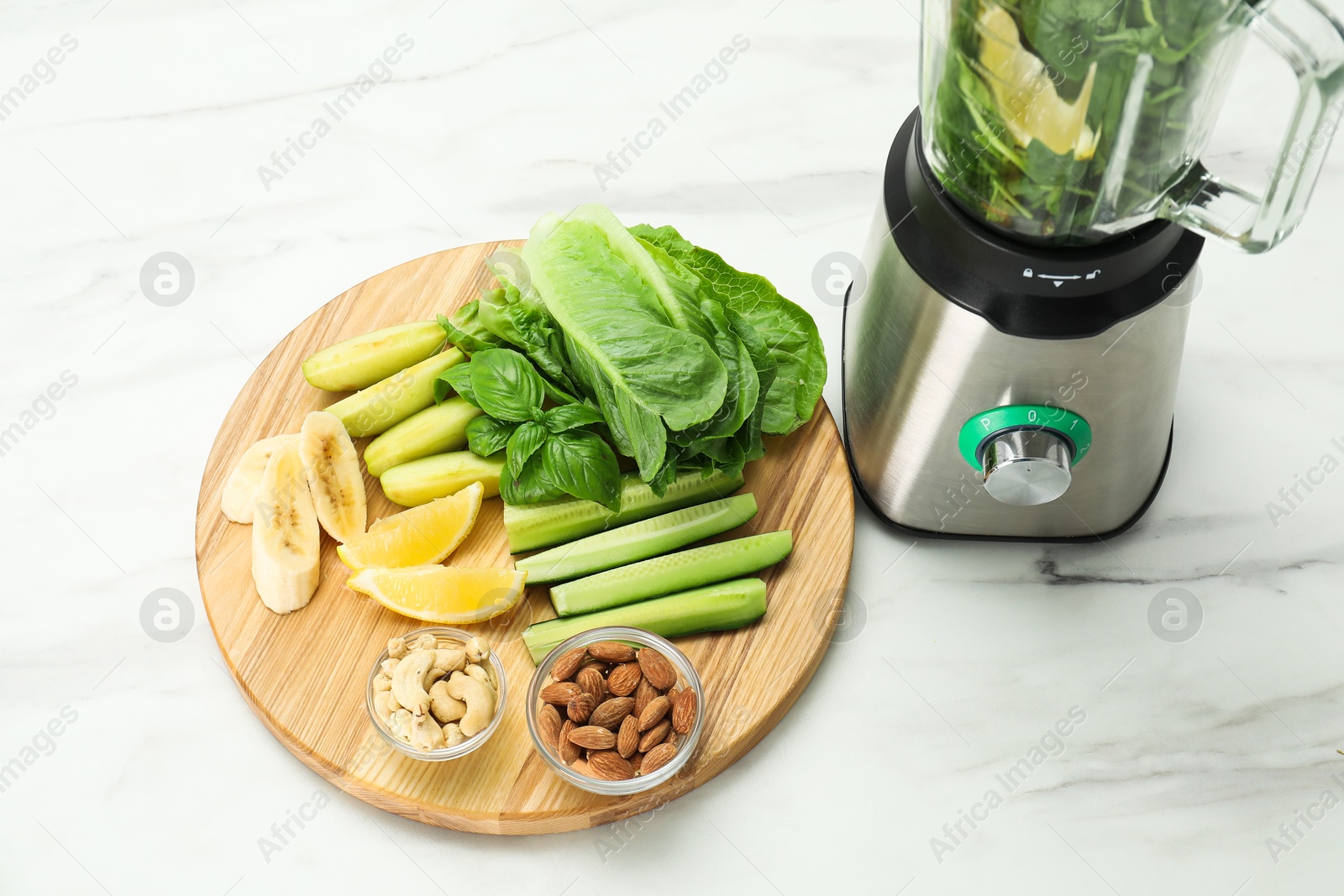 Photo of Modern blender with smoothie and ingredients on white marble table