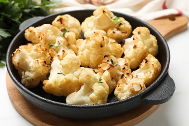 Tasty baked cauliflower in baking pan on white table, closeup