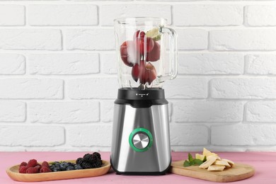 Photo of Blender and fresh ingredients on pink wooden table