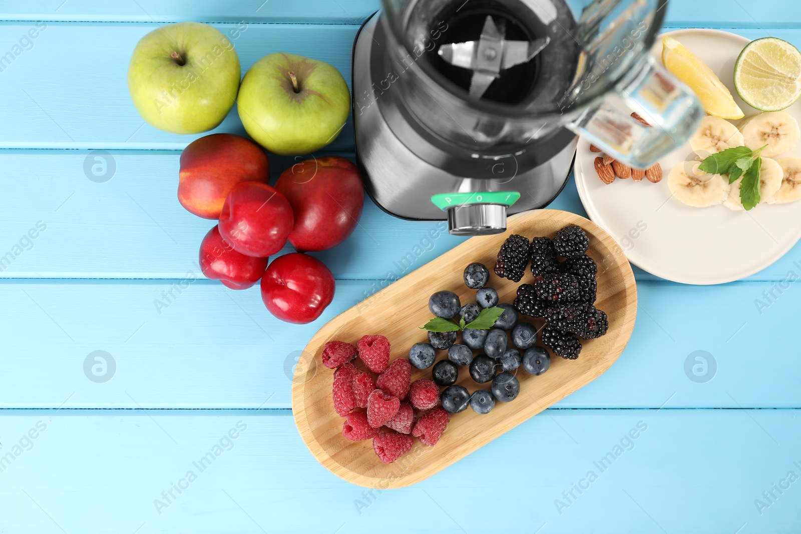 Photo of Blender and fresh ingredients on light blue wooden table, top view