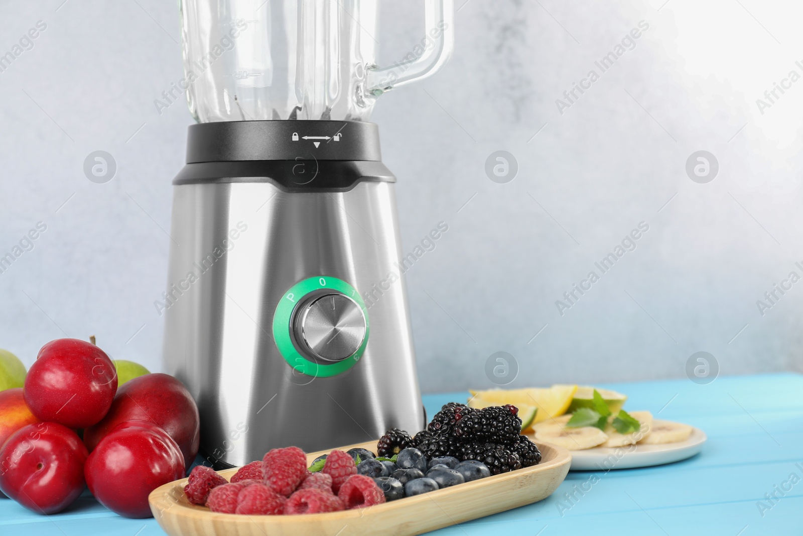 Photo of Blender and fresh ingredients on light blue wooden table