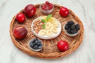 Photo of Delicious fruits, berries and nuts on white marble table