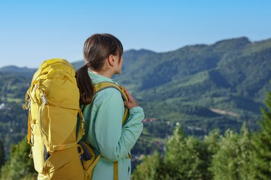 Young woman with backpack in beautiful mountains, space for text