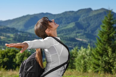 Photo of Young woman in sunglasses with backpack in beautiful mountains