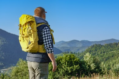 Man with backpack in beautiful mountains, space for text