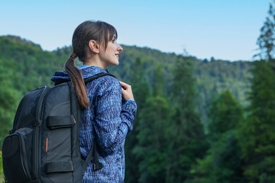 Woman with backpack in beautiful mountains, space for text