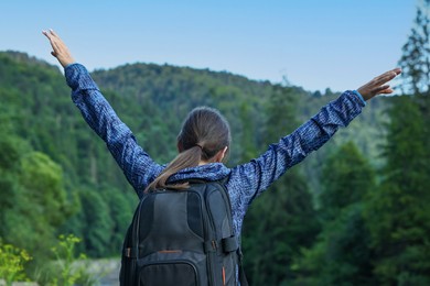 Photo of Woman with backpack in beautiful mountains, back view