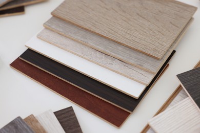 Photo of Different samples of wooden flooring on white table, closeup