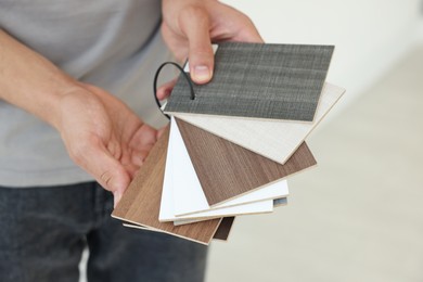 Photo of Man with samples of wooden flooring indoors, closeup