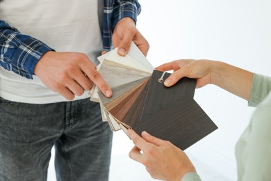 Photo of People choosing samples of wooden flooring indoors, closeup