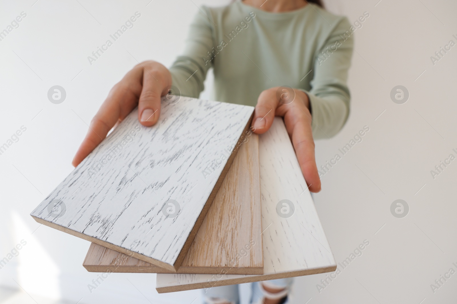 Photo of Woman with samples of wooden flooring indoors, closeup