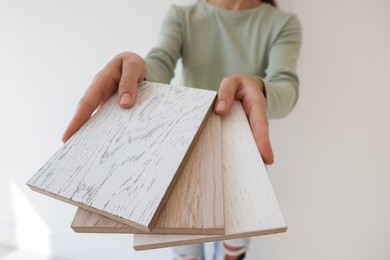 Photo of Woman with samples of wooden flooring indoors, closeup