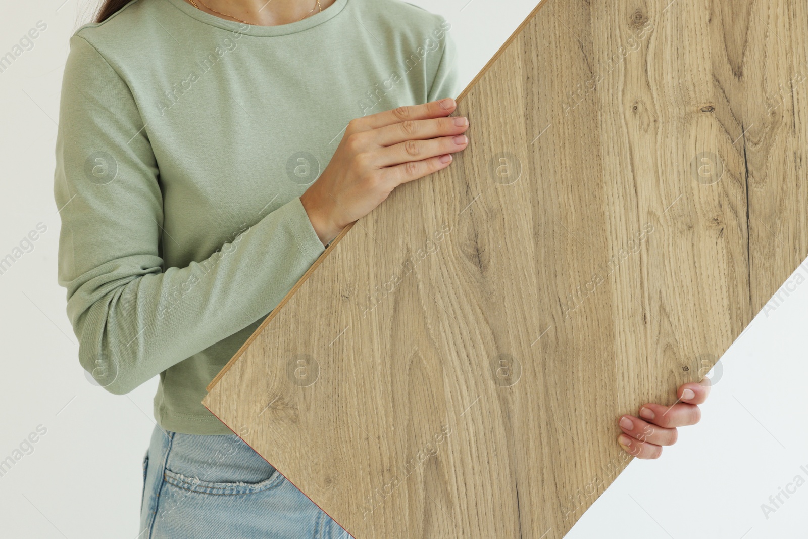 Photo of Woman with sample of wooden flooring indoors, closeup