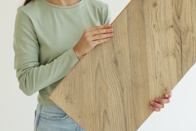 Photo of Woman with sample of wooden flooring indoors, closeup