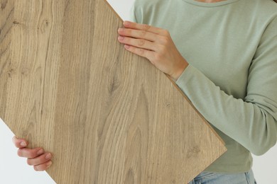 Photo of Woman with sample of wooden flooring indoors, closeup