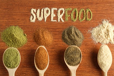 Photo of Word Superfood and different healthy powders on wooden table, flat lay