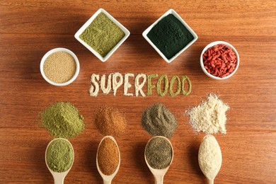 Photo of Word Superfood and different healthy powders on wooden table, flat lay