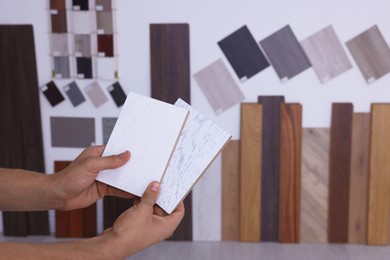 Photo of Man with different samples of wooden flooring indoors, closeup