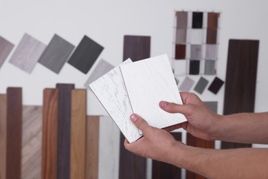 Photo of Man with different samples of wooden flooring indoors, closeup