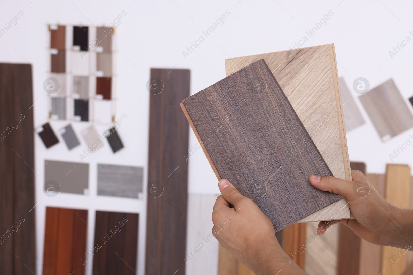 Photo of Man with different samples of wooden flooring indoors, closeup