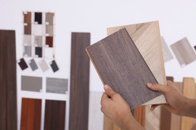 Photo of Man with different samples of wooden flooring indoors, closeup