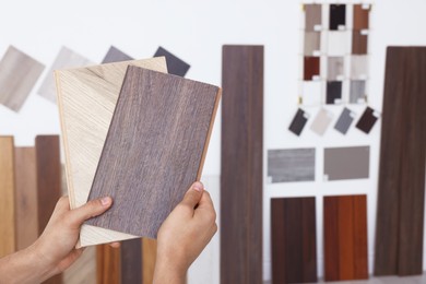 Photo of Man with different samples of wooden flooring indoors, closeup