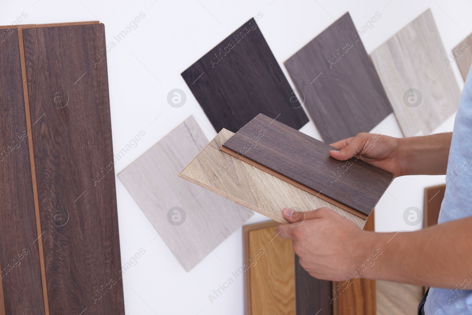 Photo of Man with different samples of wooden flooring indoors, closeup