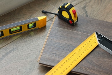 Photo of Measuring tools and laminate flooring pieces on wooden surface, closeup