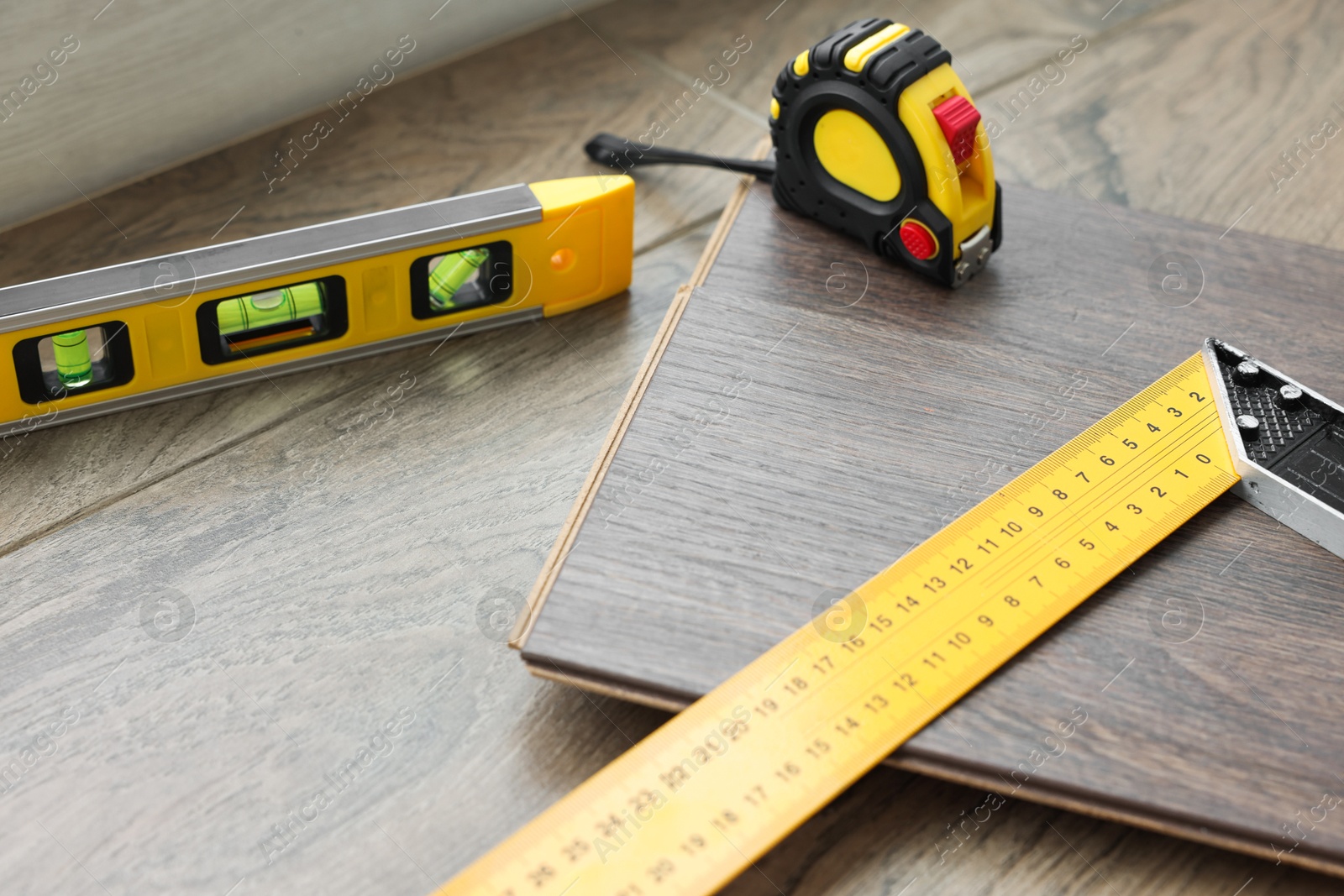 Photo of Measuring tools and laminate flooring pieces on wooden surface, closeup