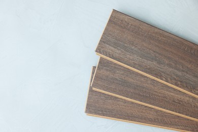 Photo of Laminate flooring pieces on grey textured surface, top view. Space for text