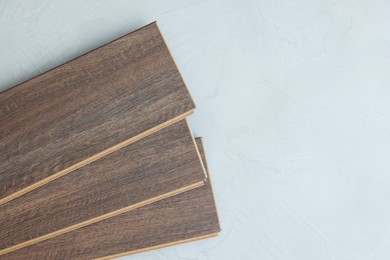 Photo of Laminate flooring pieces on grey textured surface, top view. Space for text