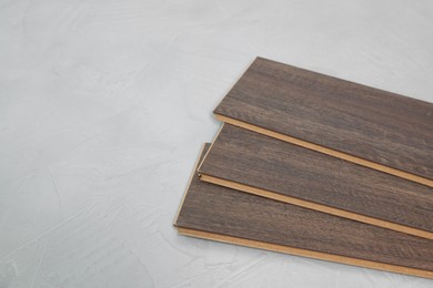 Photo of Laminate flooring pieces on grey textured surface, closeup