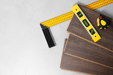 Photo of Different measuring tools and laminate flooring pieces on grey textured surface