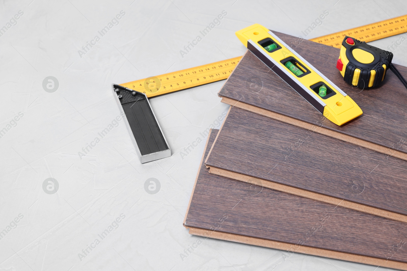 Photo of Different measuring tools and laminate flooring pieces on grey textured surface