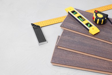 Photo of Different measuring tools and laminate flooring pieces on grey textured surface