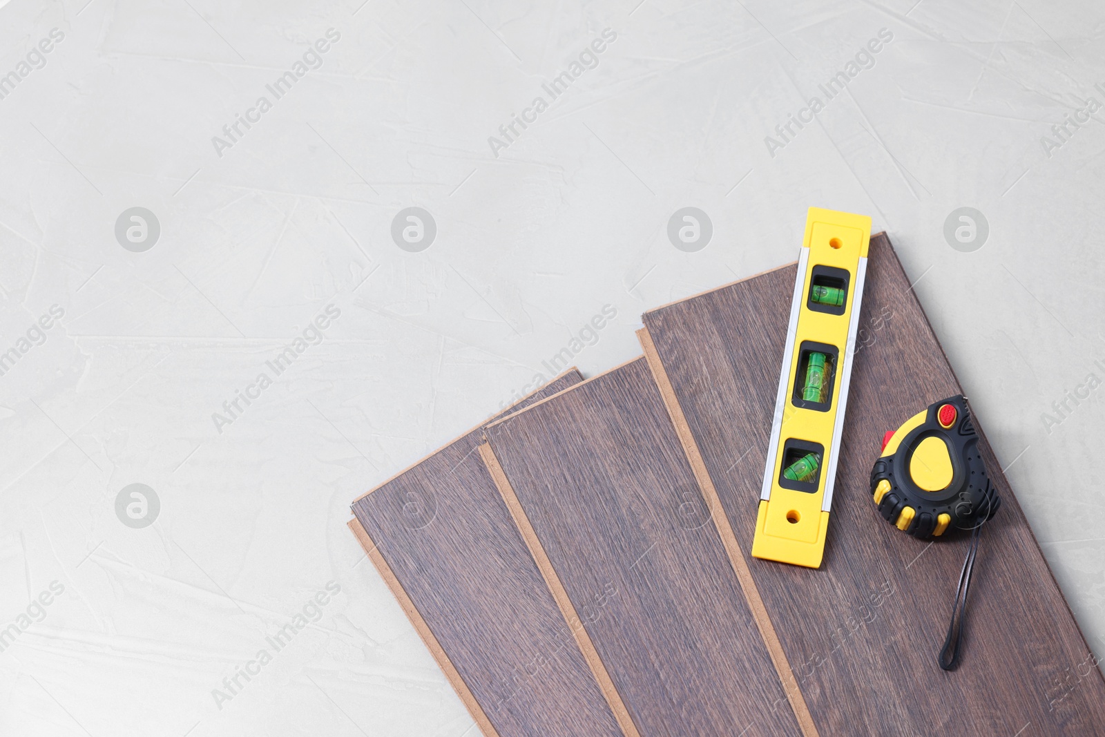 Photo of Different measuring tools and laminate flooring pieces on grey textured surface. top view. Space for text