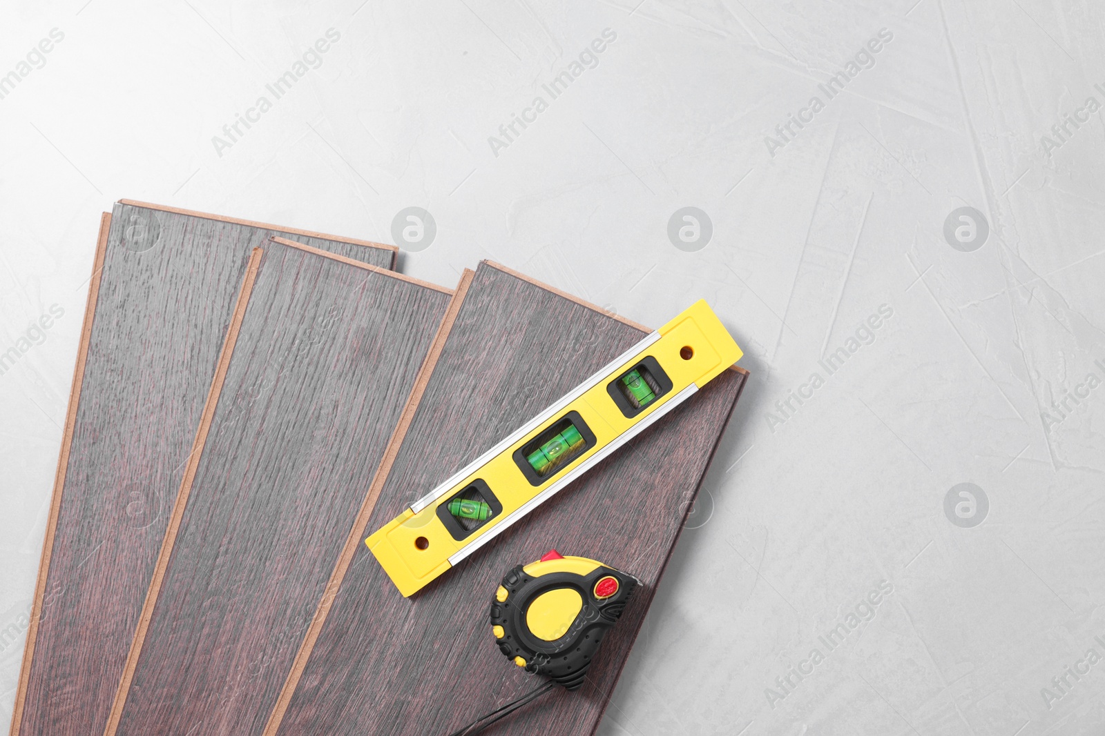 Photo of Different measuring tools and laminate flooring pieces on grey textured surface. top view. Space for text