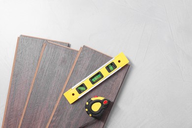 Photo of Different measuring tools and laminate flooring pieces on grey textured surface. top view. Space for text