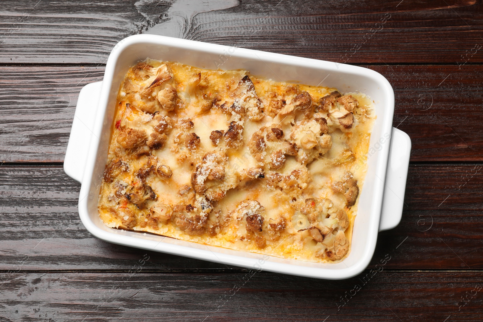 Photo of Tasty baked cauliflower in baking dish on wooden table, top view