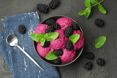 Photo of Delicious blackberry sorbet with fresh berries in bowl and spoon on gray textured table, flat lay