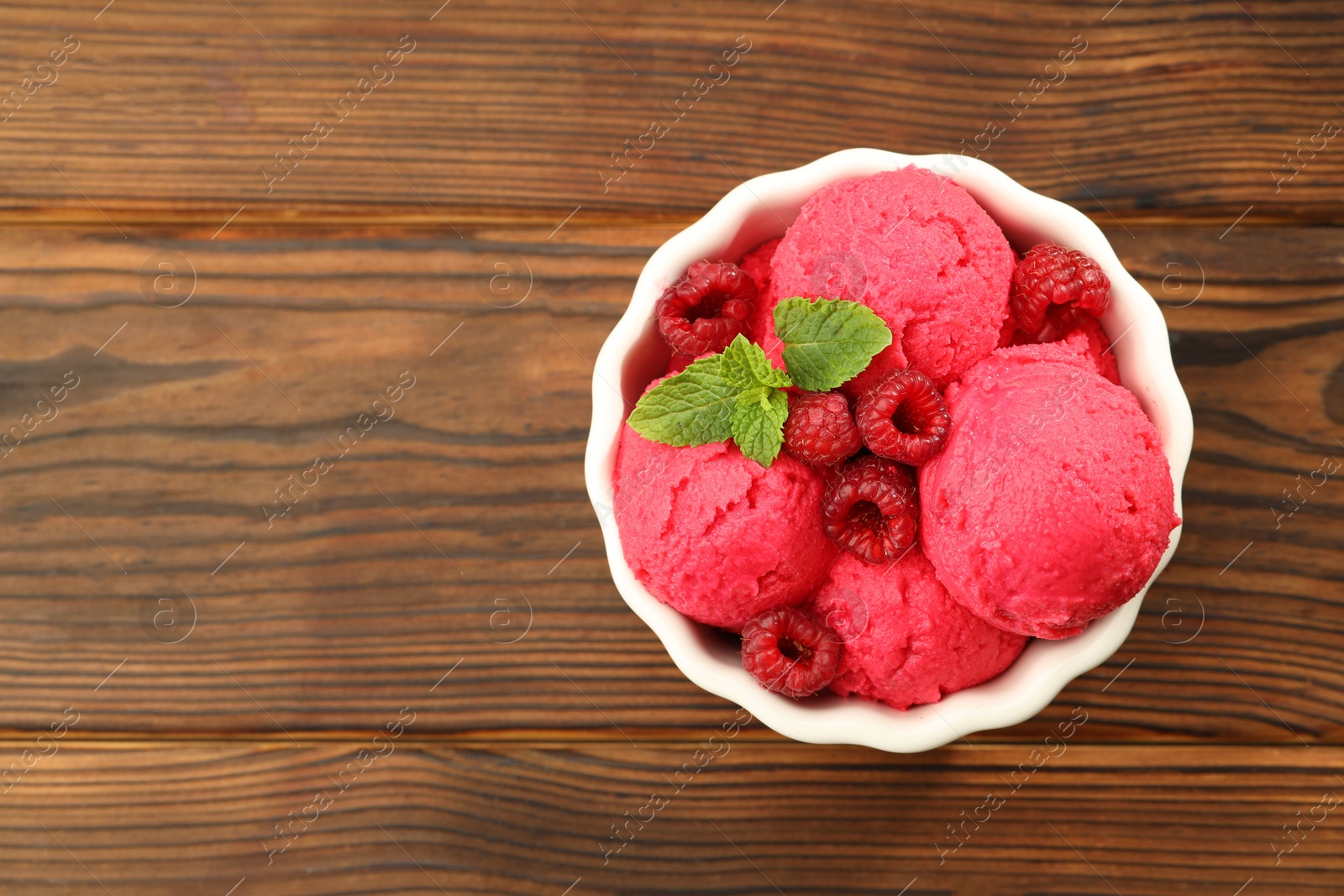 Photo of Delicious raspberry sorbet, fresh berries and mint in bowl on wooden table, top view. Space for text