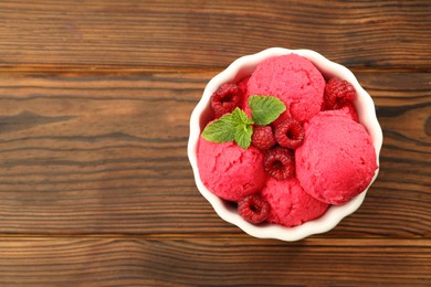 Photo of Delicious raspberry sorbet, fresh berries and mint in bowl on wooden table, top view. Space for text