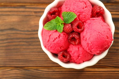 Photo of Delicious raspberry sorbet, fresh berries and mint in bowl on wooden table, top view