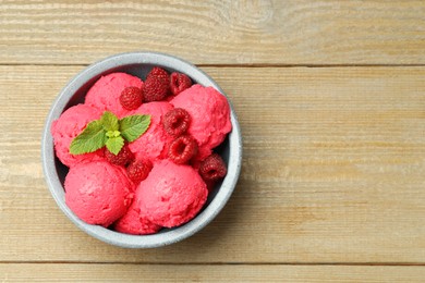 Photo of Delicious raspberry sorbet, fresh berries and mint in bowl on wooden table, top view. Space for text