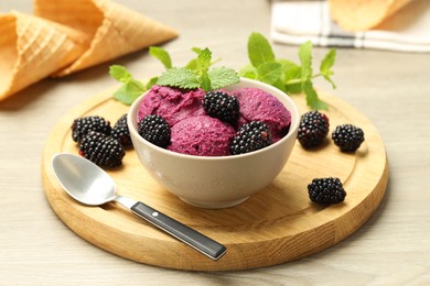 Photo of Delicious blackberry sorbet with fresh berries in bowl and spoon on wooden table